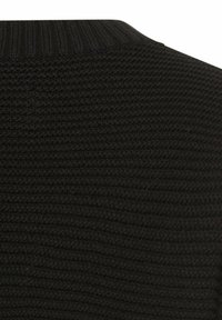 Nærbillede af sort strikstof med en ribstrikket krave, der viser detaljeret tekstureret syning.