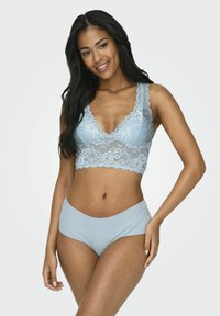 Il bralette in pizzo azzurro chiaro presenta bordi scallop e un design a V. Abbinato a una mutandina a vita alta liscia e coordinata per un aspetto senza soluzione di continuità.