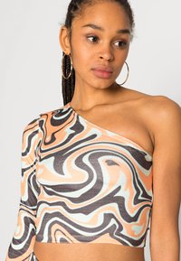 Top assimétrico de um ombro com um padrão ondulado multicolorido em pêssego, preto e menta, confeccionado em um tecido elástico.