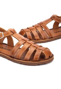 Sandali chiusi in pelle marrone con molteplici cinturini, fibbia regolabile alla caviglia e suole in gomma piatte progettate per un uso casual.