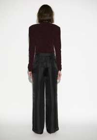 Bordeaux glinsterende lange mouwen top gecombineerd met brede zwarte satijnen broek, met een soepele textuur en een hoog ontwerp in de taille.