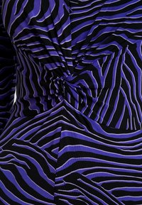 Violetti ja musta mekko, jossa on kierretty solmusuunnittelu ja rohkeita, aaltoilevia raitoja eri levyisyyksillä sileällä kankaalla.