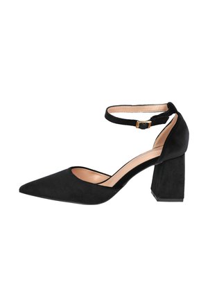 Zapato de tacón de ante negro con puntera puntiaguda y un grueso tacón cuadrado. Presenta una correa ajustable en el tobillo con un hebilla dorada. Superficie texturizada.