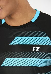 Svart atletisk tröja med korta ärmar, med en ljusblå accent vid kragen och diagonala randmönster i olika nyanser av blått.