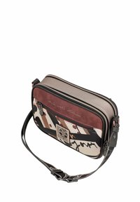 Bolso cruzado compacto en materiales mixtos; presenta gamuza rosa, patrones geométricos en negro, beige y marrón, con cierre de cremallera y correa ajustable.