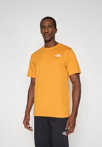 Κοντομάνικη βαμβακερή μπλούζα σε ζωντανό χρώμα μουσταρδί. Διαθέτει μικρό λευκό λογότυπο στο πάνω αριστερό μέρος του στήθους.