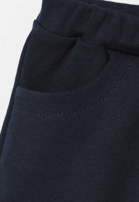 Granatowe spodnie dresowe wykonane z miękkiej bawełny, z przednią kieszenią o zaokrąglonym brzegu i widocznym przeszyciem. Nadają się do codziennego noszenia.