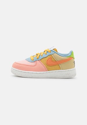 Sneaker Nike low-top con pannelli multicolore in rosa, blu, beige, verde e arancione, lacci gialli e suola bianca maculata.