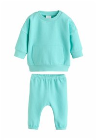 Šviesiai mėlynas medvilninis dviejų dalių komplektas su ilgomis rankovėmis ir priekine kišene ant džemperio bei derančiais kelnėmis su elastinga juosmens juosta.