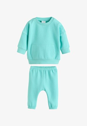 Set in cotone azzurro chiaro composto da una felpa a maniche lunghe con tasca frontale e pantaloni abbinati con elastico in vita.