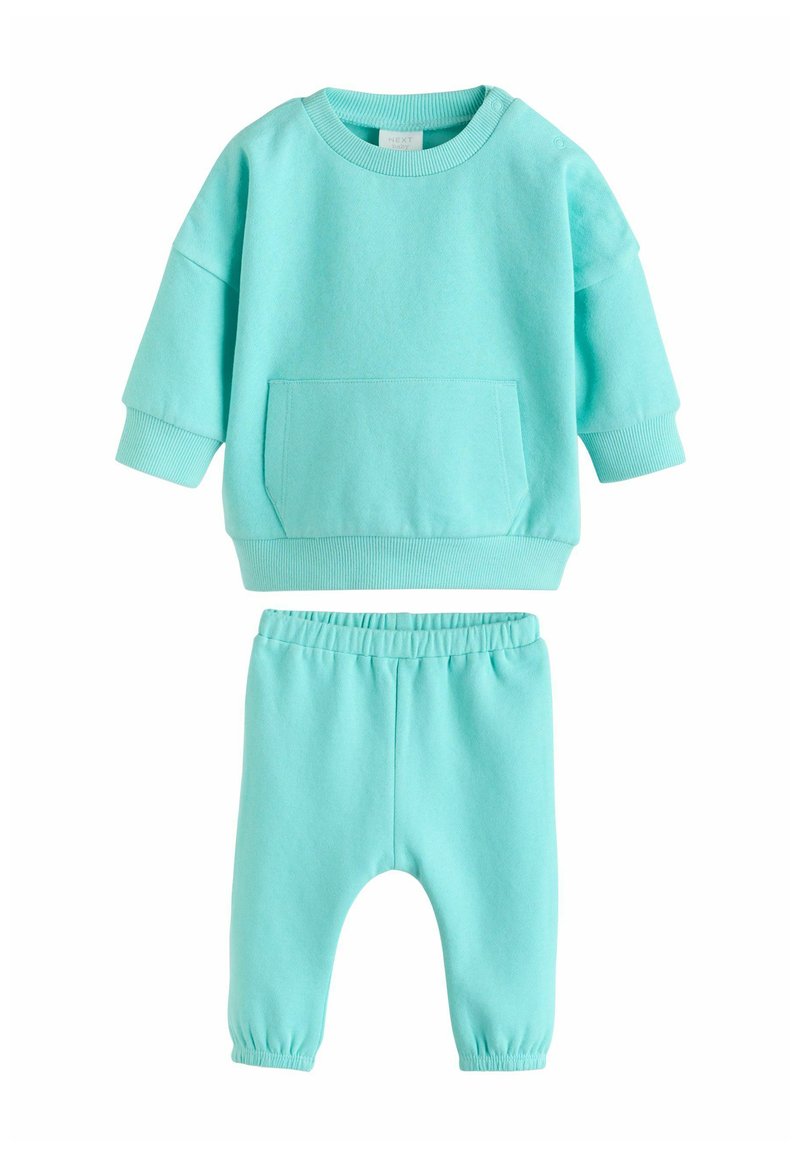Šviesiai mėlynas medvilninis dviejų dalių komplektas su ilgomis rankovėmis ir priekine kišene ant džemperio bei derančiais kelnėmis su elastinga juosmens juosta.