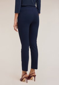 Námořnické kalhoty slim fit z hladkého materiálu. Mají pasový lem, detaily na zadním švu a jsou v kombinaci s vínovými sandály na podpatku.