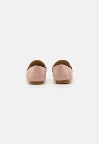 Pink suede loafers with a low heel, rounded toe, and minimalist design. Soft texture and clean lines characterize the shoe's appearance.