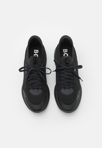 Svarta sportskor med en texturerad mesh-överdel, dämpande sula och matchande snören. Logotypen visas på innersulorna och på sidan.