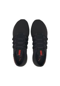 Zapatillas deportivas negras con una parte superior de malla transpirable, seis tiras elásticas para el cordón y un logo rojo en la lengüeta y el talón. Diseño de punta redonda.