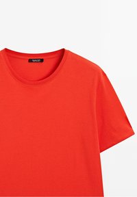 T-shirt en coton rouge uni à manches courtes, col rond et étiquette visible au dos du cou.