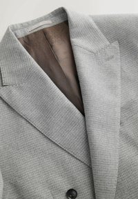 Grau kariertes Blazer mit einem strukturierten Stoff, ausgestattet mit einem breiten Revers, einem Einzelknopfverschluss und einer gemusterten braunen Futter.