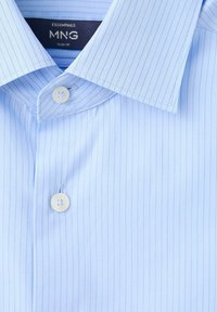 Chemise habillée slim bleu clair à fines rayures verticales avec boutons blancs, col ouvert dévoilant une étiquette de marque noire.