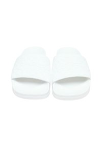 Sandales blanches à semelle plate, dotées d'une bride texturée aux motifs subtils et d'un design à bout ouvert, fabriquées à partir d'un matériau synthétique durable.