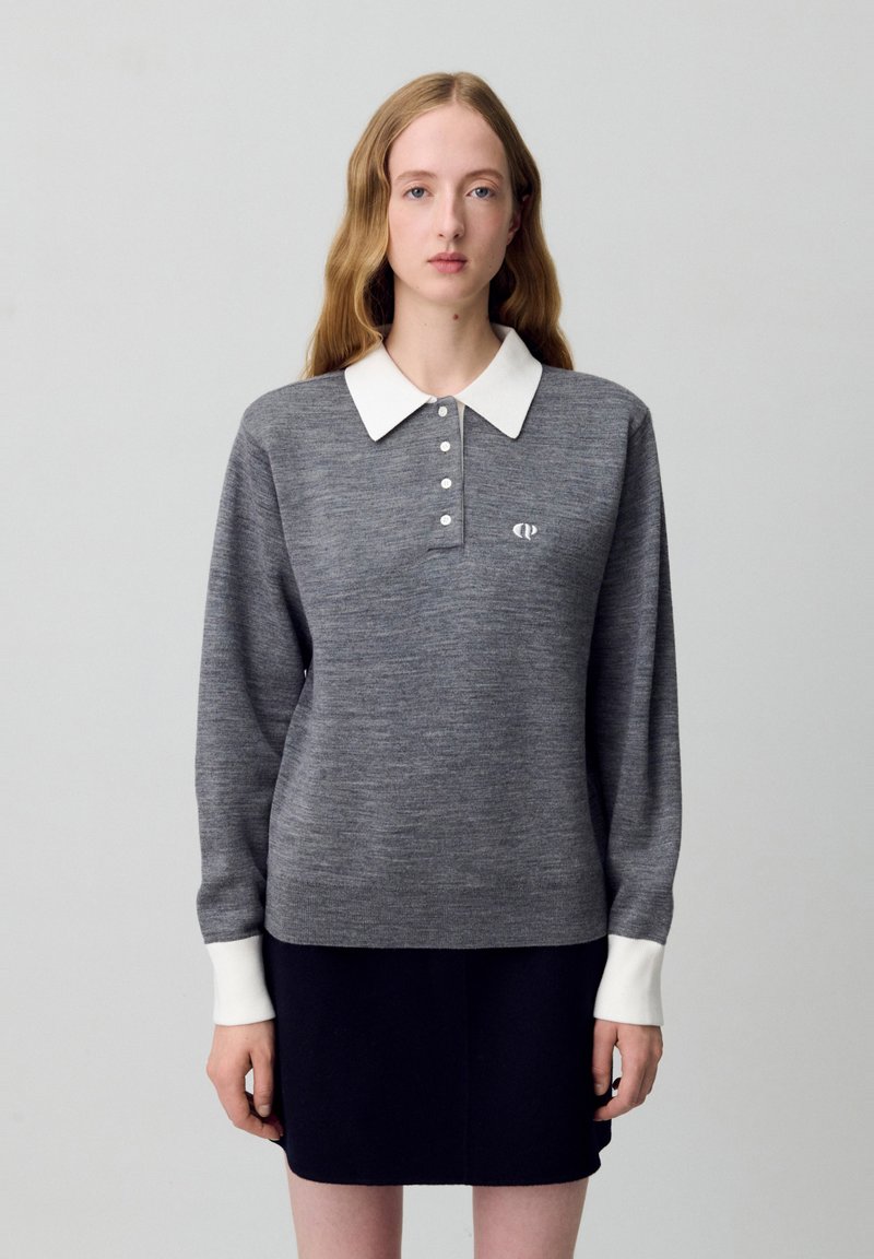 Maglia polo grigia a maniche lunghe con colletto bianco, bottoni e logo sul petto. Realizzata in tessuto a maglia con una superficie liscia.