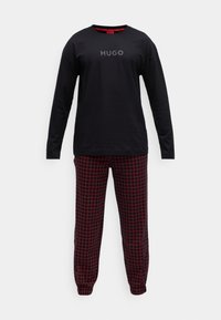 Schwarzes Langarmoberteil mit grauem "HUGO"-Logo, kombiniert mit roten karierten Schlafanzughosen. Weicher, lässiger Stoff mit elastischen Bündchen an den Knöcheln.