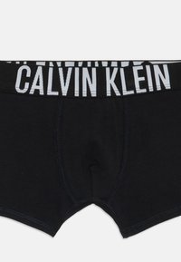 Črne moške bokserice s širokim pasom, ki se ponašajo z drznim belim napisom "Calvin Klein".
