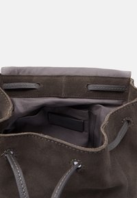 Szary zamszowy worek z wnętrzem wykończonym miękkim materiałem. Posiada zapięcie na sznurki oraz widoczną metkę marki wewnątrz. Minimalistyczny design.