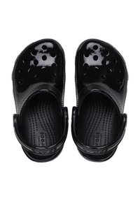 Czarne klapki wykonane z błyszczącego materiału z okrągłymi otworami na górze, teksturowana wkładka i regulowany pasek z tyłu dla pewnego dopasowania.