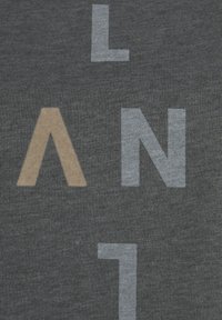 Graues T-Shirt mit großen, bedruckten Buchstaben in Beige und Hellgrau. Der Stoff hat eine weiche Textur mit einem subtilen Melange-Muster.