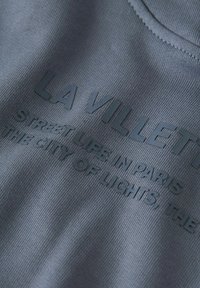 Szary sweatshirt z teksturowanej tkaniny, z wypukłym czarnym napisem: "LA VILLETTE STREET LIFE IN PARIS THE CITY OF LIGHTS."