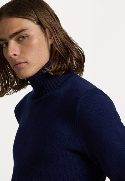 Pulover cu guler înalt de culoare bleumarin, dintr-un tricot moale, cu o croială ajustată. Prezintă un guler înalt și o textură netedă pe corp.