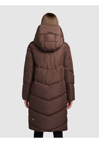 Brązowa długa kurtka puchowa z kapturem, ozdobiona pikowanymi wzorami w kształcie jodełki, o gładkiej powierzchni i małym logo przy dolnym brzegu.