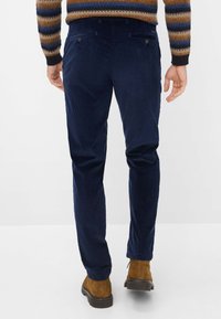 Helleblaue Cordhose mit vertikaler Rippung, vier Taschen und Knopfdetails. Kombiniert mit braunen Wildleder-Stiefeletten.