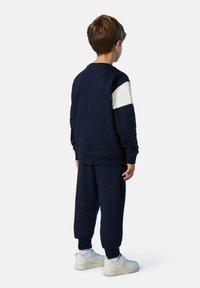 Marineblaues Sweatshirt und Jogginghosen aus weichem Stoff, mit einem weißen Akzent am linken Ärmel. Die Jogginghosen haben einen lässigen Schnitt und Bündchen.