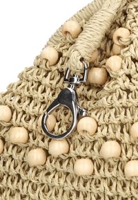 Natuurlijk geweven tas met houten kralenaccenten, voorzien van een zilverkleurige sluiting en een gevlochten touwhandvat.