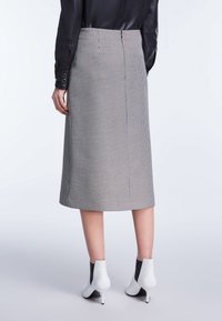 High-waisted, midi-lange rok in een zwart-wit houndstoothpatroon. Stof is textuur met een gladde afwerking. Achterste ritssluiting.