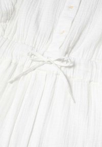 Robe en tissu blanc texturé avec des boutons sur le devant et un lien de taille noué, présentant un détail élastique froncé à la taille.