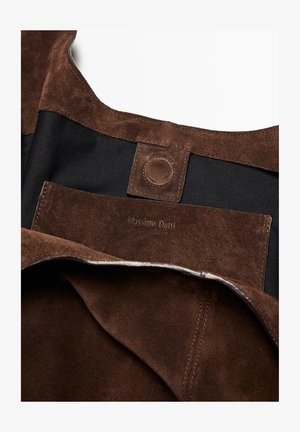 Intérieur d'un sac en suédine marron avec doublure en tissu noir. Contient un logo en relief et un détail de fermeture à pression. Finition texturée évidente.