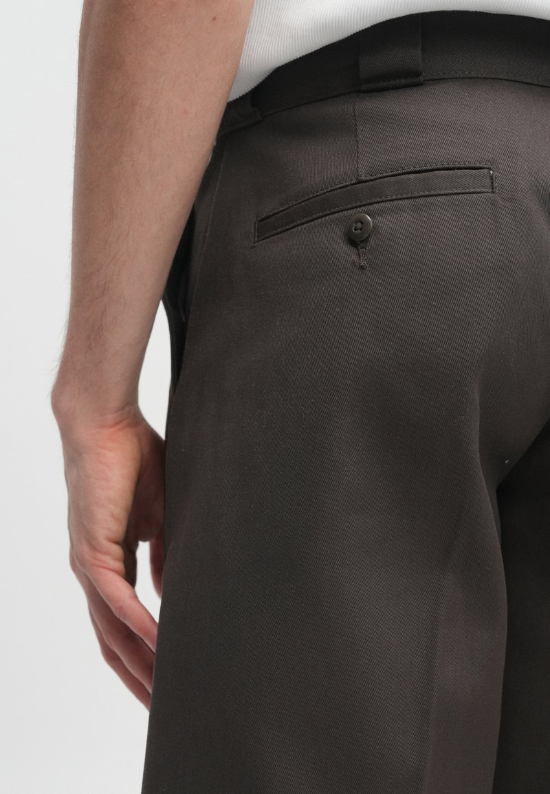 Mørkebrune skræddersyede bukser lavet af struktureret stof, med en baglomme med knaplukning og en glat livrem.