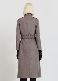 Manteau long marron ajusté avec un col montant, ceinture à la taille et gants en cuir noir. Texture lisse avec peu de détails.