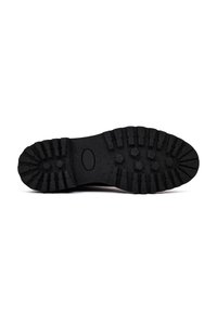 Suola di scarpa in gomma nera con scanalature profonde, una finitura strutturata e un'incavatura ovale. Progettata per trazione e durata in diverse condizioni.