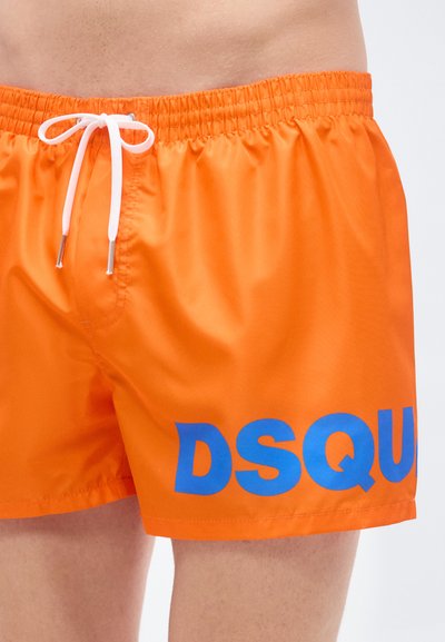 Πορτοκαλί μαγιό με ελαστική μέση και λευκό κορδόνι, διακοσμημένο με μεγάλο μπλε λογότυπο "DSQUARED" στην αριστερή πλευρά.