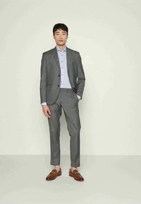 Grijs twee-delig kostuum met een slim fit, voorzien van een enkelgeknoopte jas, lichtblauw shirt en bruine instappers. Soepele stof en op maat gemaakt ontwerp.
