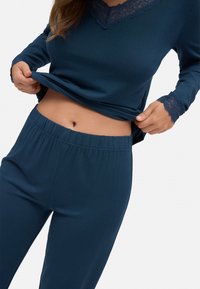 Conjunto de ropa de casa en azul marino con mangas largas, detalle de encaje en el escote y en los puños, y cintura elástica. Textura de tela suave y lisa.