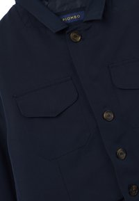 DunkelblauesJackett mit Fronttaschen, vier braunen Knöpfen und einem sichtbaren Kragenetikett mit der Aufschrift "PIOMBO."