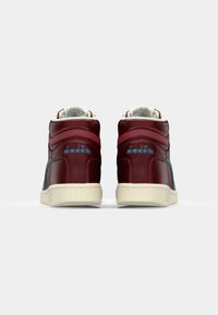 High-top sneakers in maroon and teal leather with a textured cream rubber sole; features logo and padded collar for comfort.