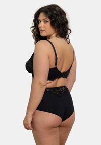 Soutien-gorge en dentelle noire avec bretelles ajustables et fermeture à crochet, associé à une culotte noire taille haute avec des accents en dentelle le long de la taille.