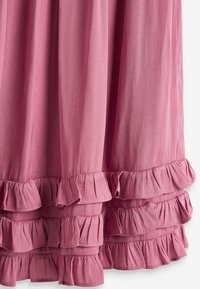 Rosa Stoffkleid mit einem fließenden Design und geschichteten Rüschen am Saum. Die weiche Textur und das leichte Material betonen den Fall.