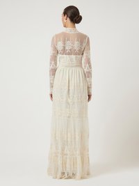 Largo vestido crema con un cuerpo de bordado transparente, acentos de encaje detallados y una falda plisada fluida. Presenta mangas largas y un cuello alto.