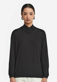 Schwarzer Pullover mit hohem Kragen und langen Ärmeln. Weiche Textur, leicht lockere Passform und minimalistisches Design ohne sichtbare Muster oder Beschläge.